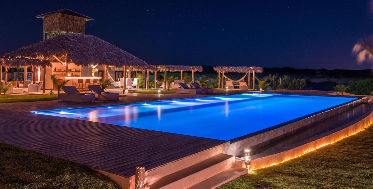 piscina iluminada a noite com bar ao fundo