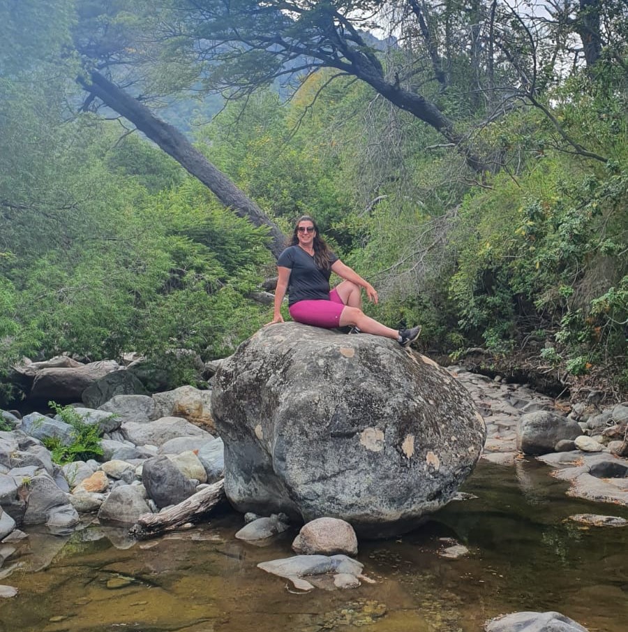 mulher sentada em pedra com rio  e natureza