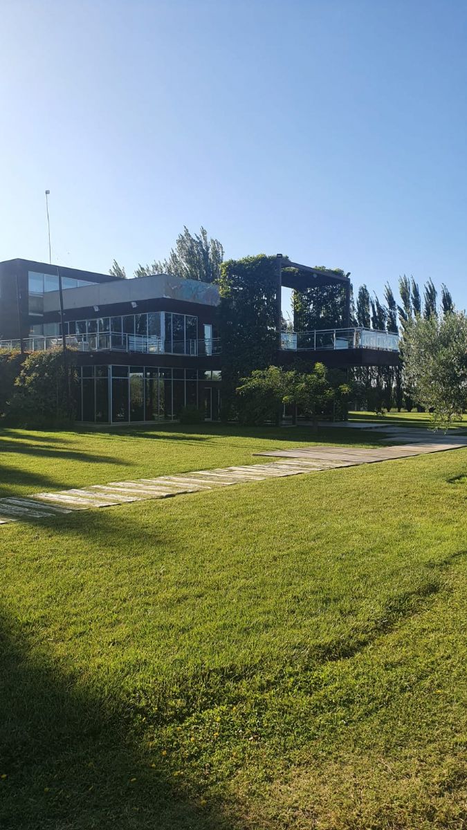 fachada lateral de prédio espelhado com céu azul e gramado