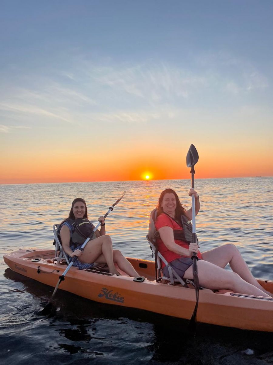 duas mulheres e caiaque no mar ao nascer do sol